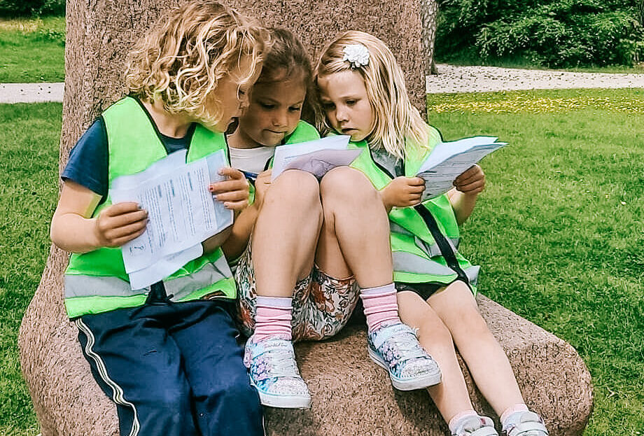 Tre barn som sitter på en skulptur i Kulåsparken. Foto.