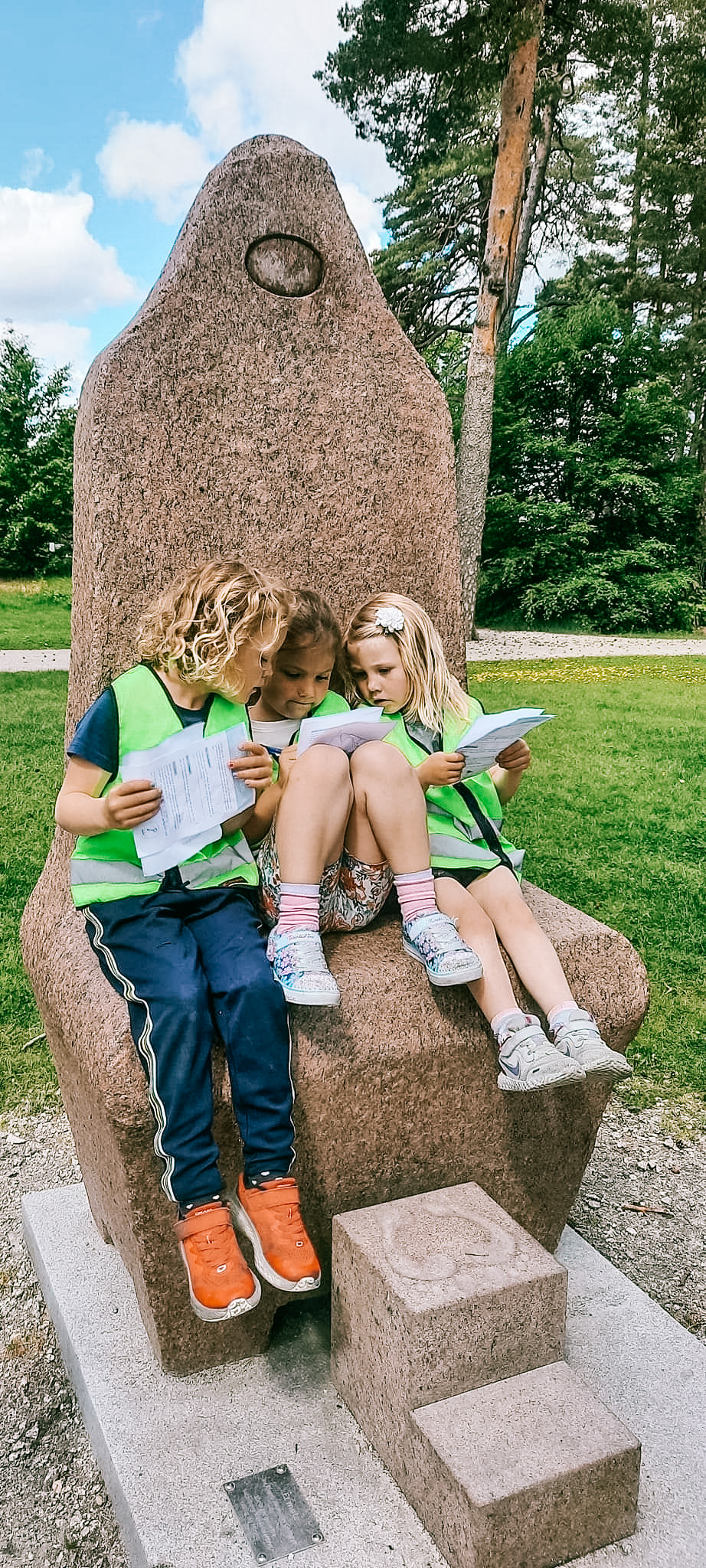 Tre barn som sitter på en skulptur i Kulåsparken. Foto.